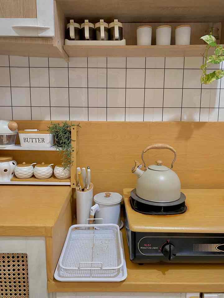 Beige and white toned kitchen space featuring wooden countertops, kettle on stove, and knife block with cozy ambiance