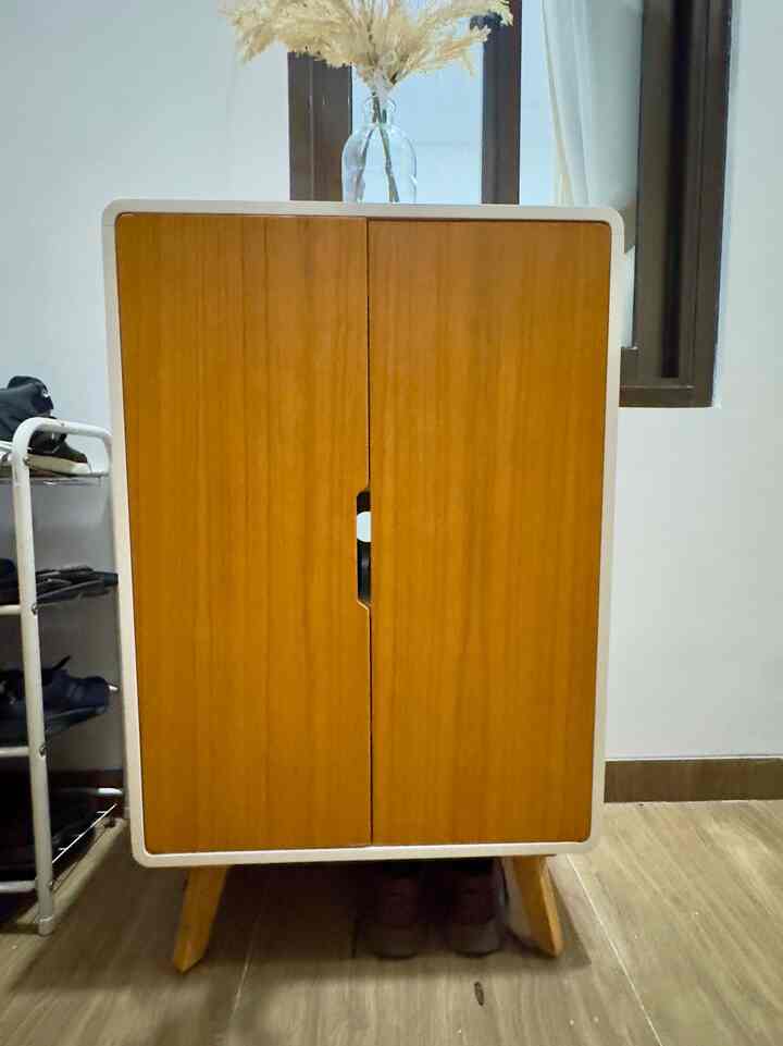 Brown-toned shoe cabinet placed in a narrow room corner with shoe rack beside it