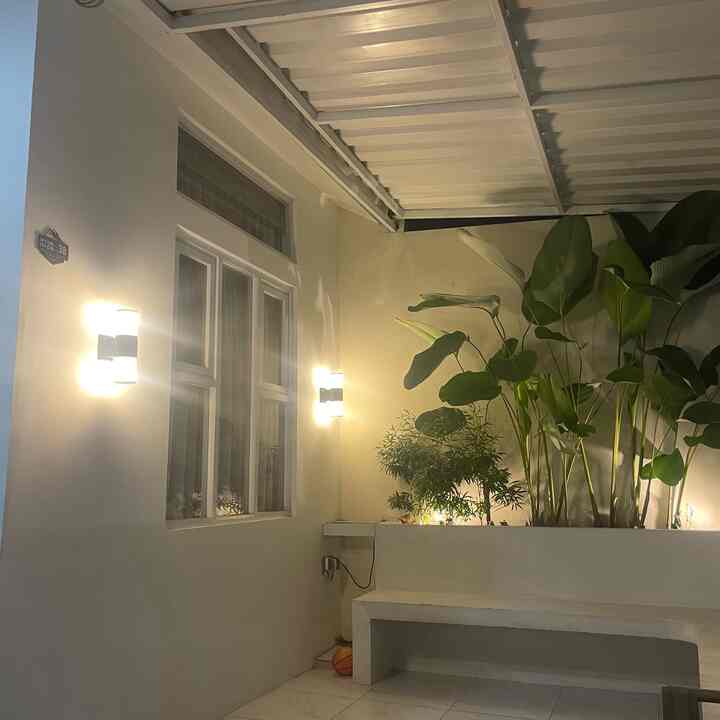 Light gray and white toned balcony featuring wall sconces and large plants, creating a serene outdoor relaxation space