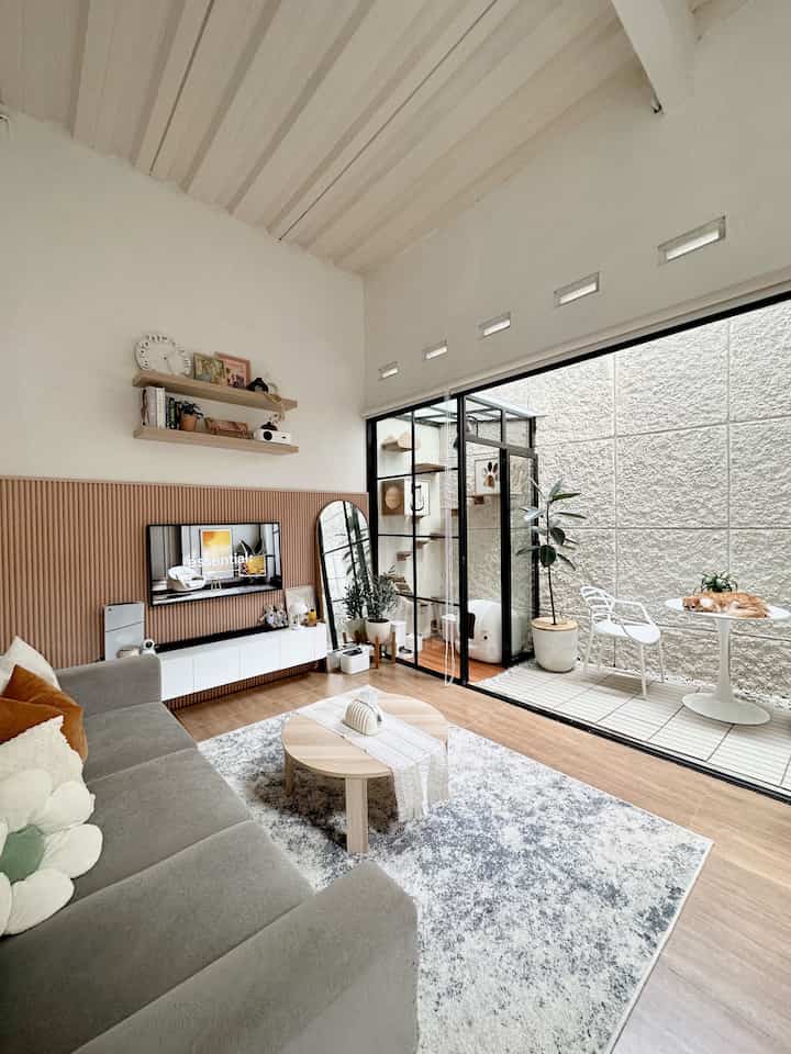 Natural tone and white living room featuring large sofa and mini courtyard creating a cozy open space