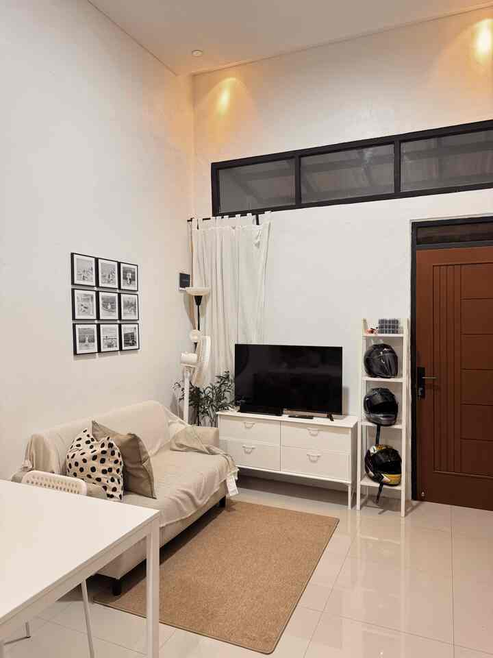 White and beige toned living room featuring a sofa and TV stand with a simple modern atmosphere