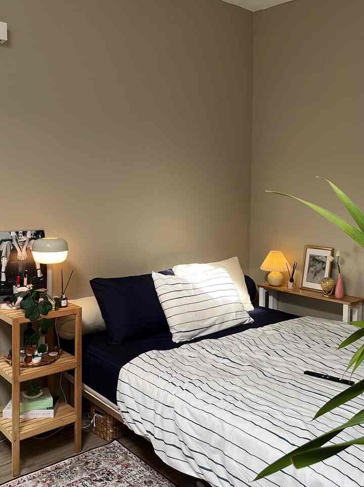 Beige-toned mid-century modern bedroom featuring wood tone furniture and white-navy bedding, creating a cozy natural atmosphere