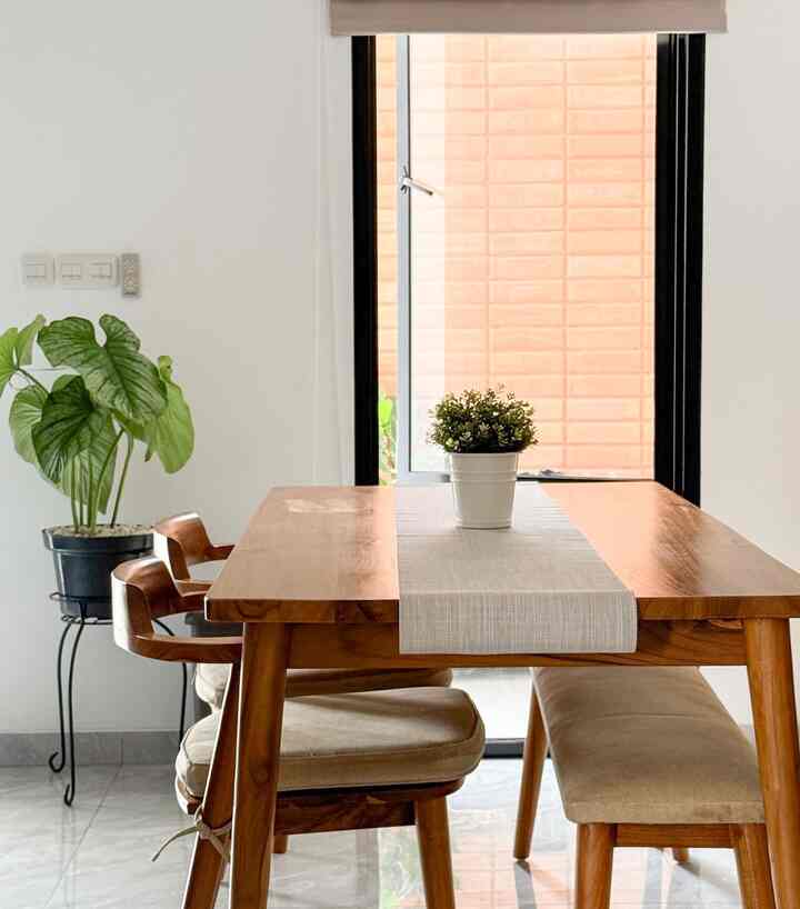 Natural dining room with white walls and warm wood tone dining table, chairs, and bench