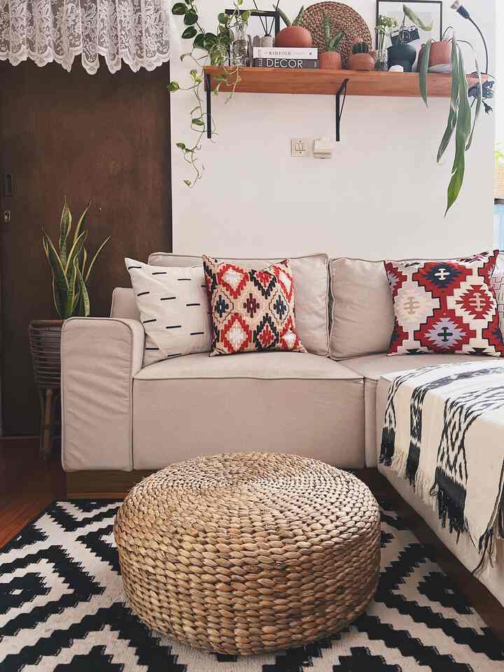 Beige and wood tone living room featuring a rattan ottoman, cushions, and plants creating a natural cozy atmosphere