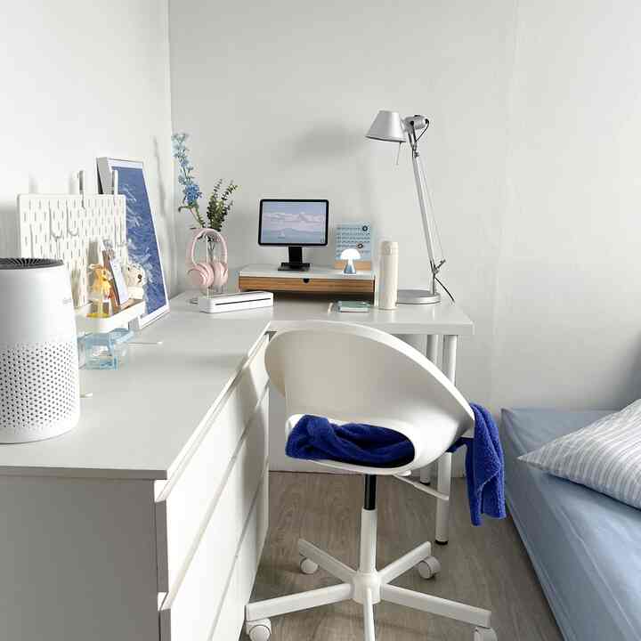 White and blue toned bedroom home office featuring a clean desk and office chair with a minimal and modern interior