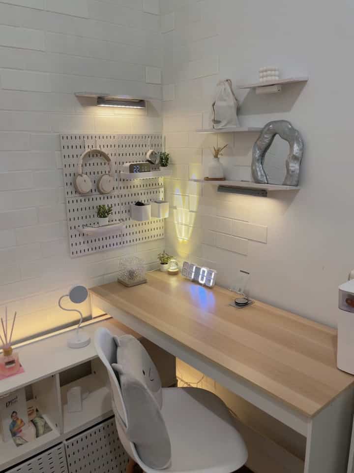 White walls and wood tone desk with organized pegboard and shelves in a small, neat home office space