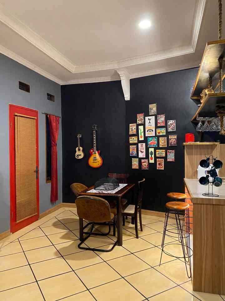 Retro style dining room with black accent wall, wooden furniture, vintage posters and bar stools creating industrial vibe