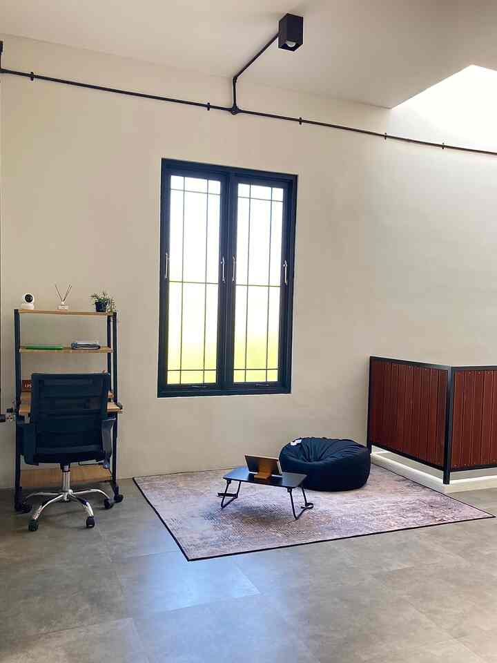 Bright white-walled industrial style second-floor home office featuring black furniture, a carpet with bean bag, and a desk setup