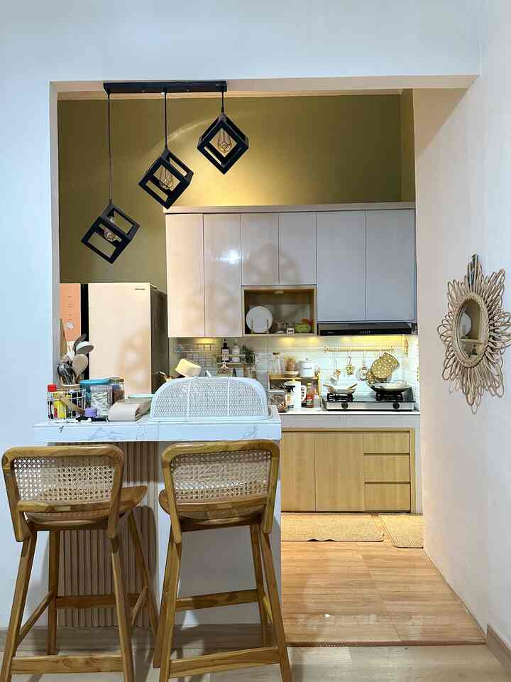 Small modern kitchen featuring wood tones and white cabinetry, with pendant lights and dining chairs centrally placed for a cozy atmosphere