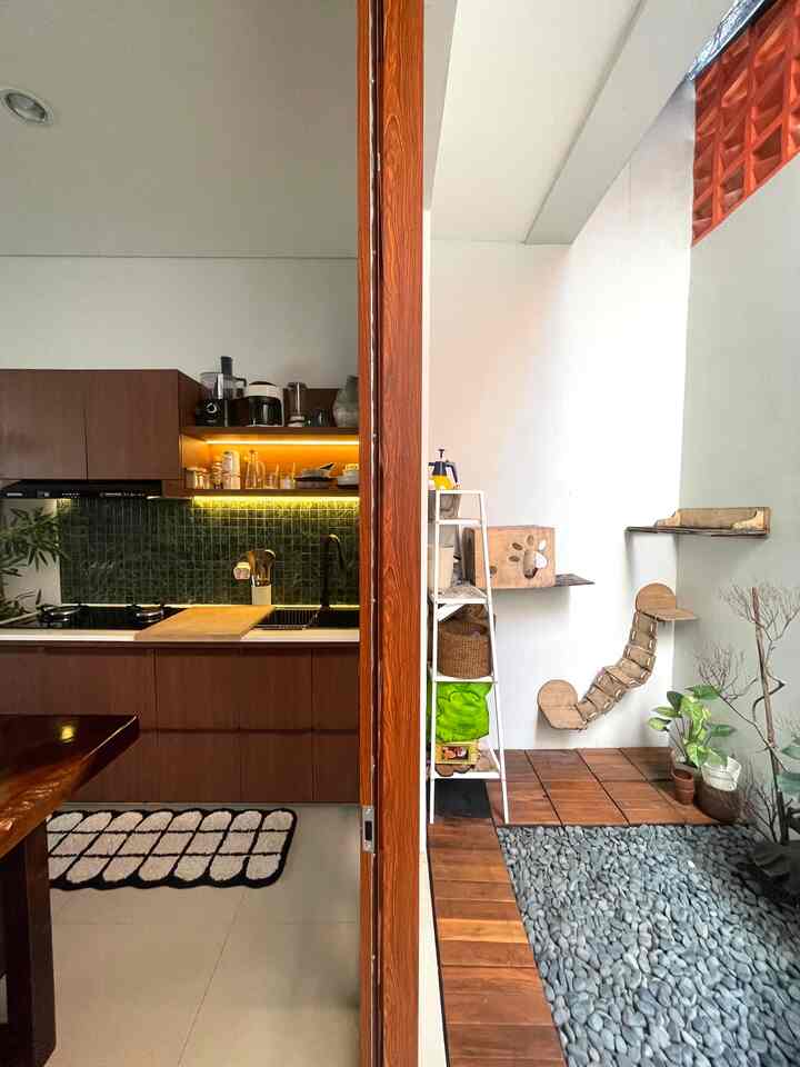 Wood tone and white walled dining room featuring a kitchen area and separated pet house space with natural elements