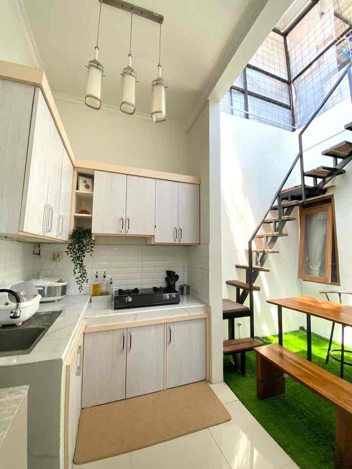 Bright white and natural wood tone kitchen and dining area in a narrow, vertical layout with natural lighting
