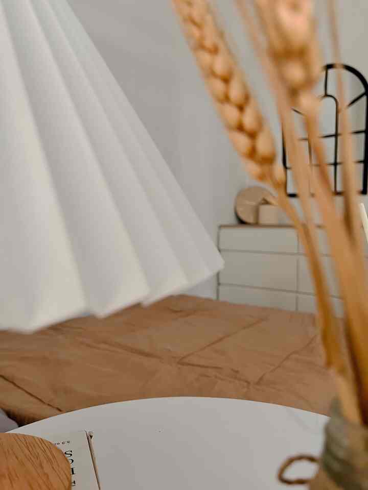 Natural toned bedroom featuring a beige bed, white pleated curtain, and dresser creating a cozy atmosphere
