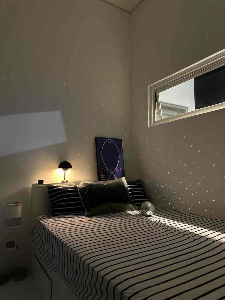 Monotone black and white bedroom featuring striped bedding and a disco ball creating a cozy night-time ambiance