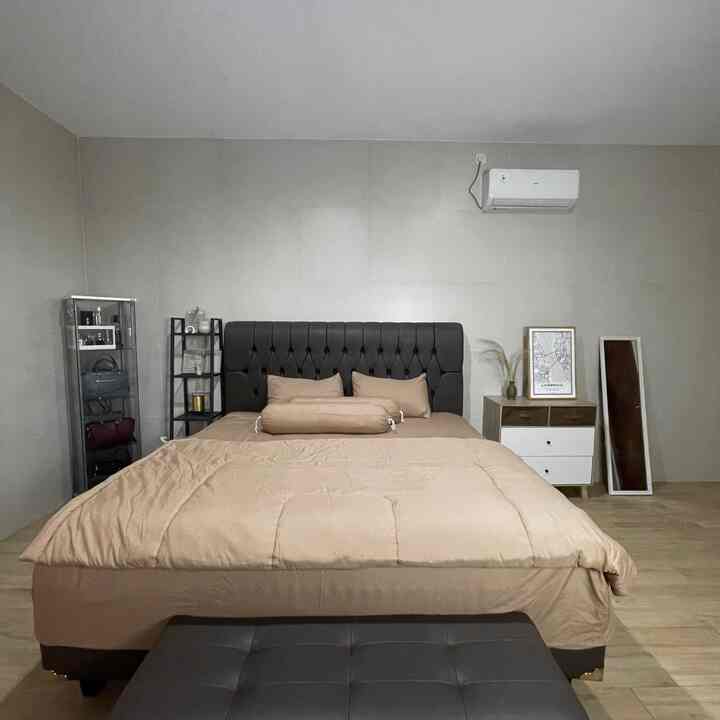 A beige and wood tone bedroom featuring a king-size bed and dresser with a simple, modern atmosphere