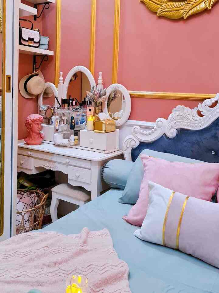 A pink and blue harmonious bedroom space featuring a vanity and velvet headboard with a romantic atmosphere