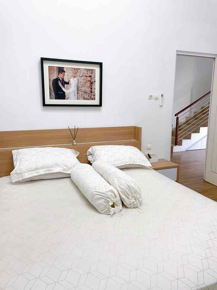A white and natural-toned bedroom featuring a wooden bed frame and crisp white bedding for a clean, cozy atmosphere