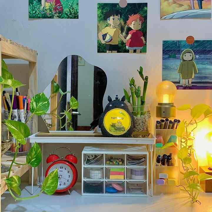 Natural-toned bedroom desk space featuring Ghibli posters and a wavy mirror with warm ambient lighting