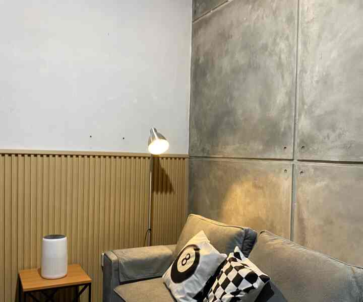 Natural-toned living room featuring brown floor lamp and gray sofa with textured wall panels