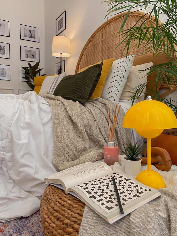 A natural-toned bedroom with white bedding and yellow table lamp and cushions, creating a cozy atmosphere