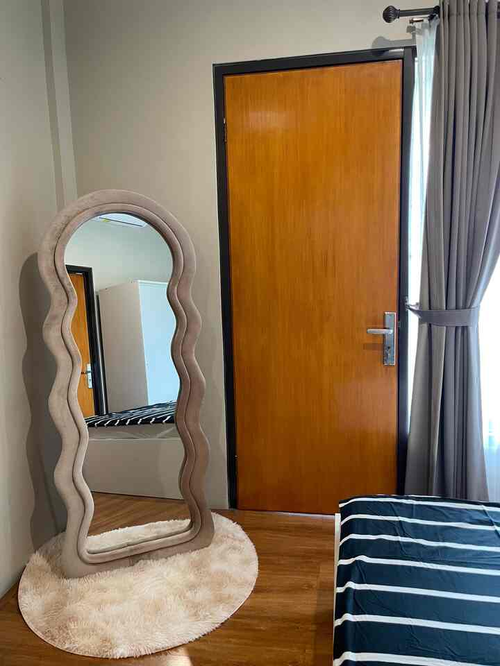 Beige-toned wavy mirror and brown wooden door in a bedroom with clean, natural modern atmosphere