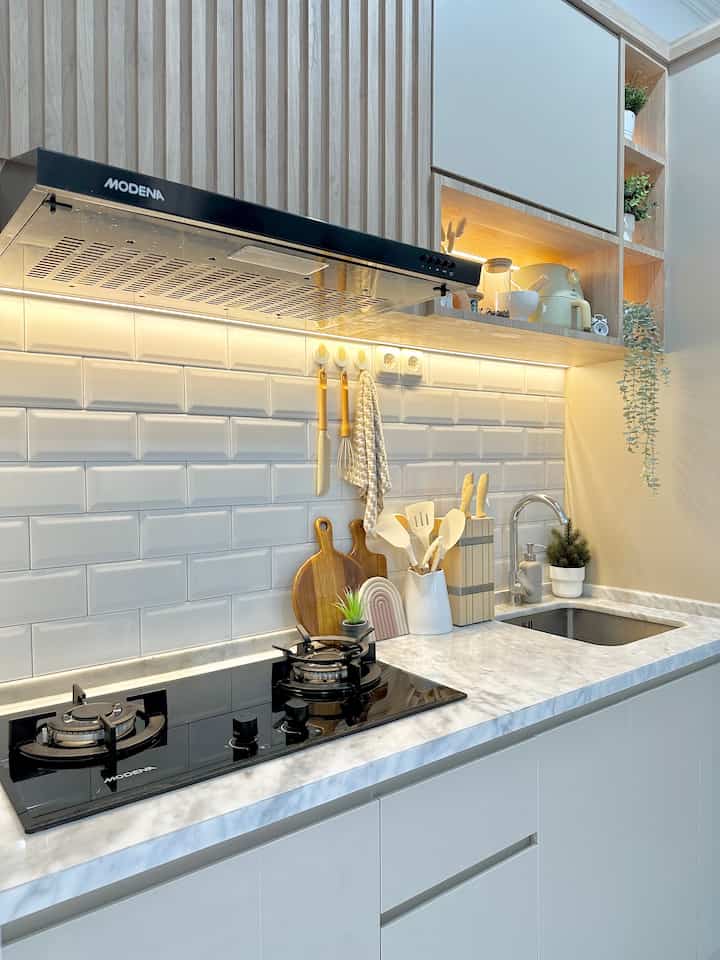 Gray and white toned kitchen space featuring organized cooking utensils and plants with a modern, cozy atmosphere