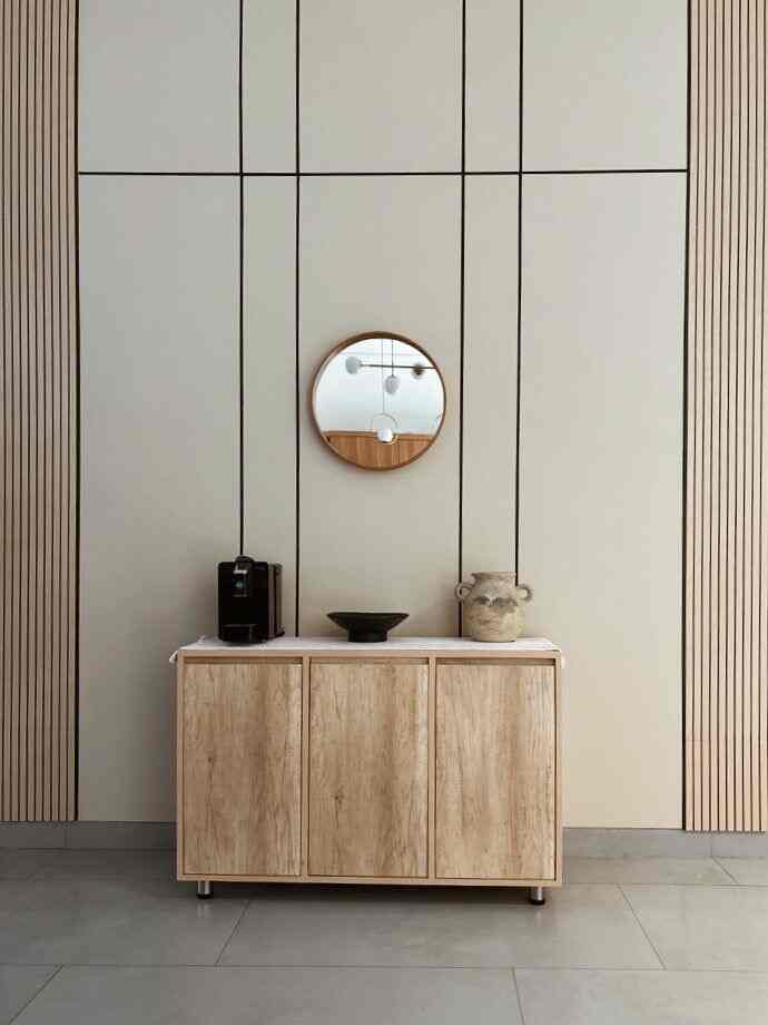 Beige and wood tone entrance space featuring a clean cabinet with a central round mirror and vase on top, creating a harmonious look