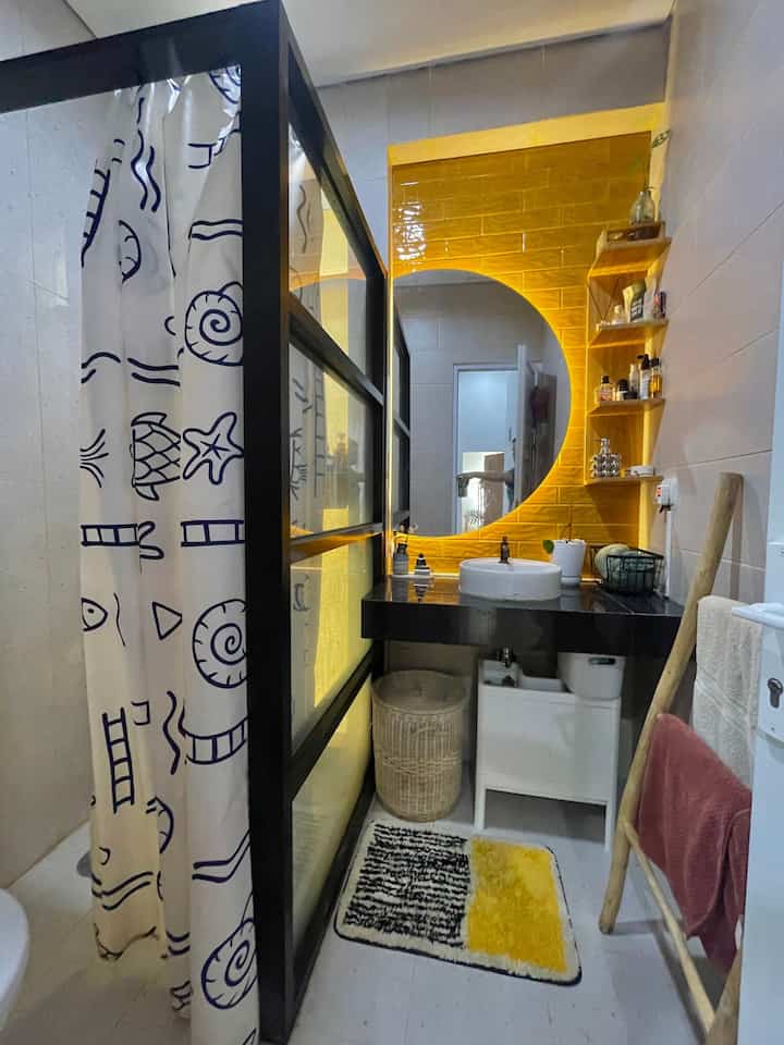 Mendekorasi kamar mandi bawaan developer ala first21.haus ;
1. Partisi aluminium kaca dan railing+tirai polyster.
untuk membatasi area shower dengan area kering (wastafle) dan area toilet. pemilihan aluminium hitam krna mengikuti meja keramik wastafle bawaan developer yg berwarna hitam. 
2. Keramik dinding warna kuning mustard.
Supaya tidak monoton dan bathroom kami jd lebih fresh.
3. Kaca Cermin setengah bulat & lampu Led.
Karena ingin punya cermin wastafle yg tidak mainstream tidak ada salahnya mencoba cermin setengah bulat ini dan ternyata menurut kami cocok dgn keramik mustardnya.
4. Rak dinding motif kayu (mdf).
Supaya bs menaruh amenities lbh rapi dan mudah dijangkau, sehingga meja wastafle tidak terkesan penuh
5. Kabinet wastafle ikea.
Solusi utk storage seperti alat-alat kebersihan, detergen & cairan pembersih lantai supaya tidak terekspos langsung namun mudah dicari.
6. Membuat tempat sabun di area shower.
Menggunakan cover keramik yg sama dengan dinding wastafle. Karna tidak disediakan oleh developer dan tidak mau terlalu banyak paku di dinding keramik, kami buat sendiri di space kaca ventilasi kamar mandi. Sehingga masih senada dengan area wastafle. 

Semoga bermanfaat 😉
#bathroomideas #bathroomtransformation #showerroom #Dekorkamarmandi #bathroominspo #bathroomdecoration 