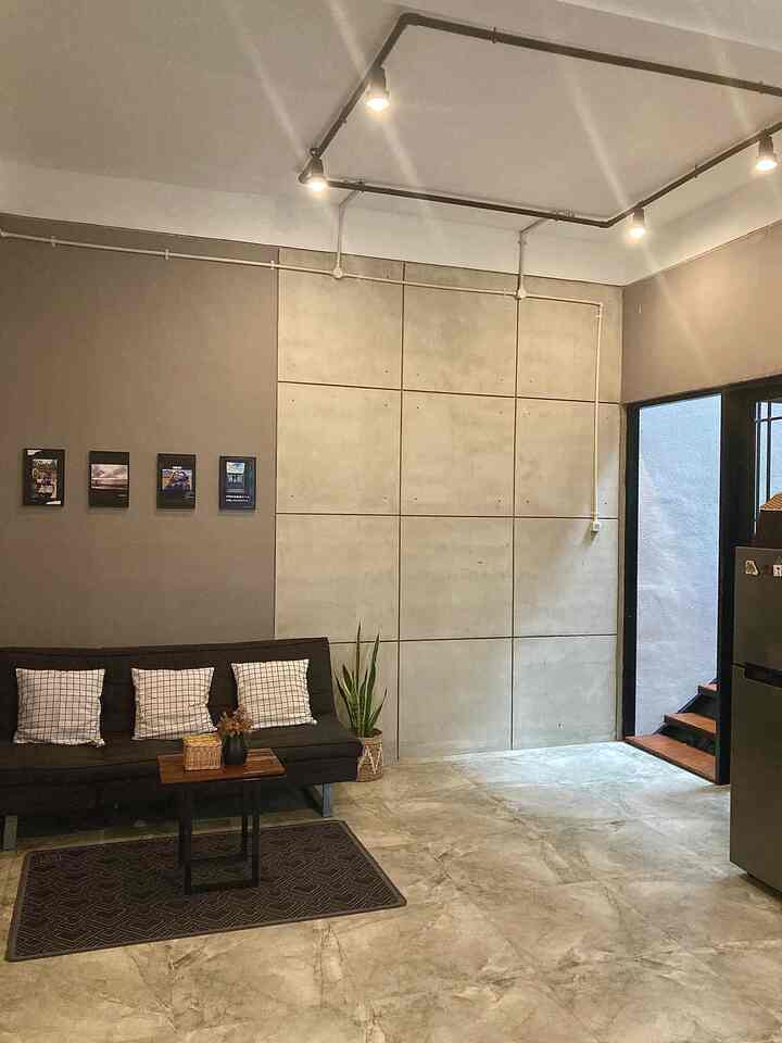 Natural modern studio apartment living room with gray concrete walls and black sofa