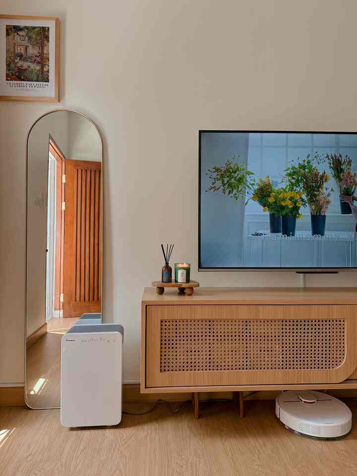 Modern and cozy living room with warm wood tones and white accents, featuring a large mirror and TV console