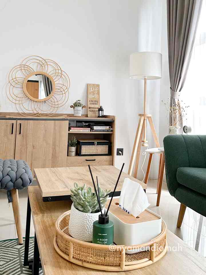 A natural-toned living room featuring a wooden cabinet, green sofa, and a rattan mirror creating a cozy atmosphere
