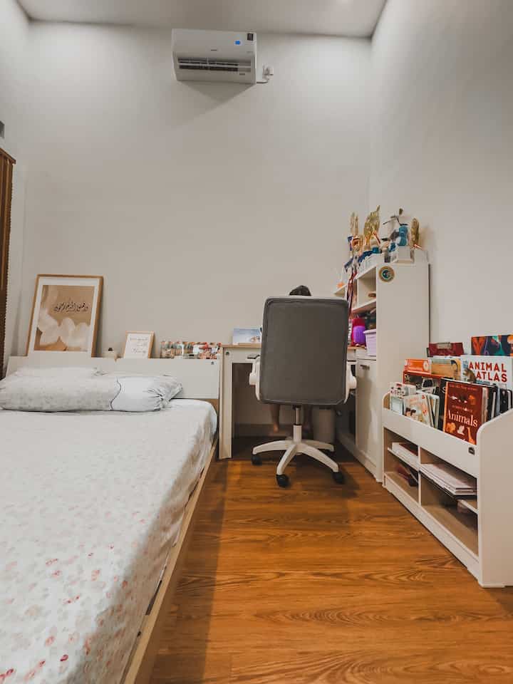 White walls and brown wood floor studio bedroom featuring a bed and desk with cozy feel