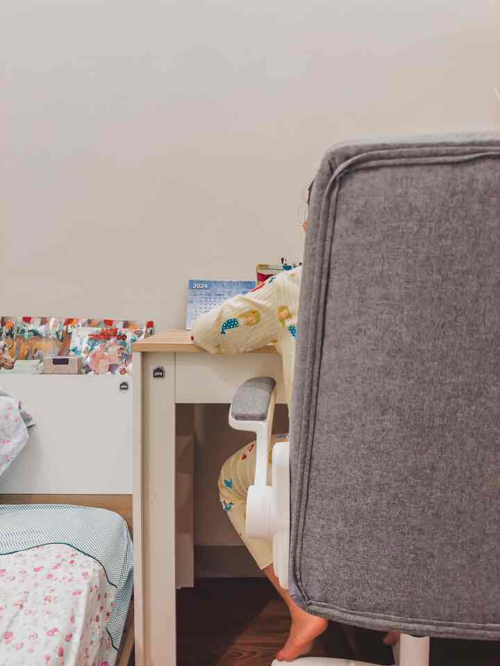 White and wood tone children's bedroom featuring a desk, nightstand, and armchair in a cozy study space