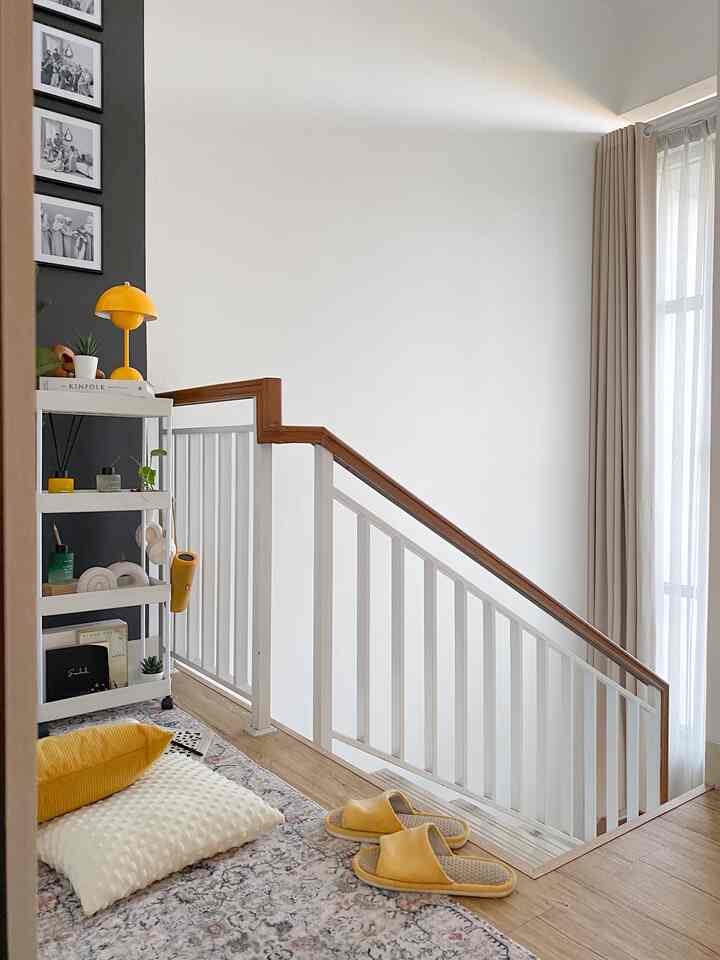 Bright balcony space featuring white walls and wood tones with yellow cushions and slippers as natural accent elements