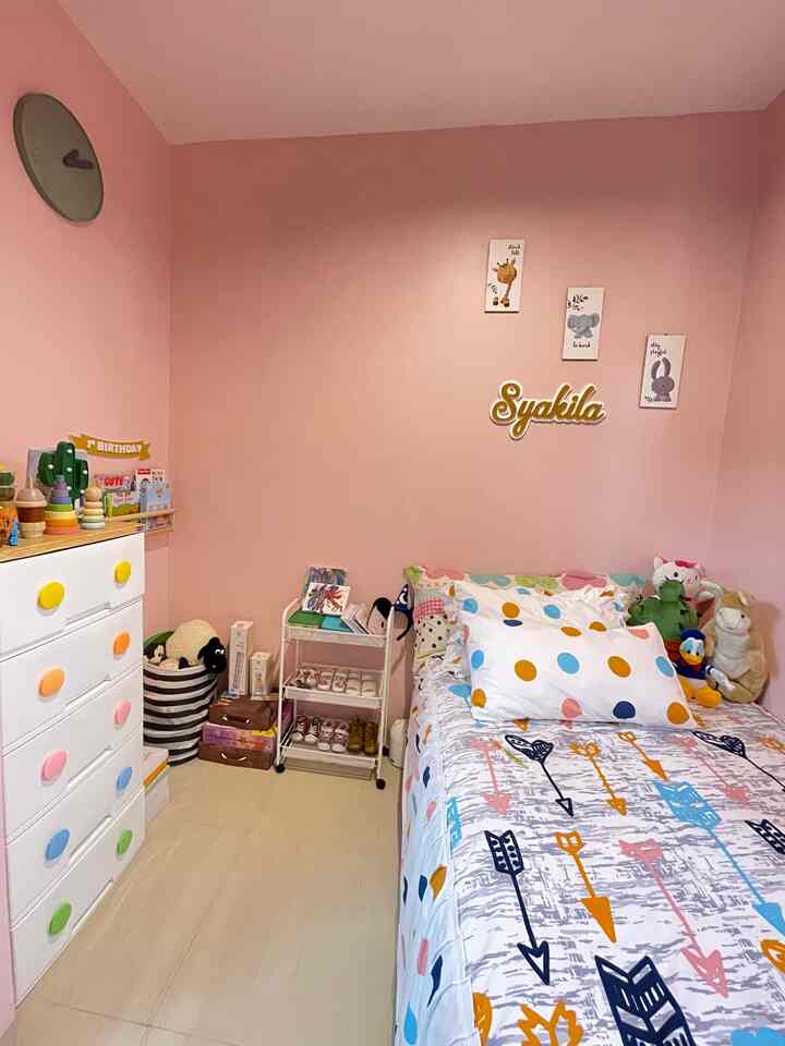 Compact kids' room with pink walls and white furniture, featuring a bed and colorful storage units creating cozy atmosphere