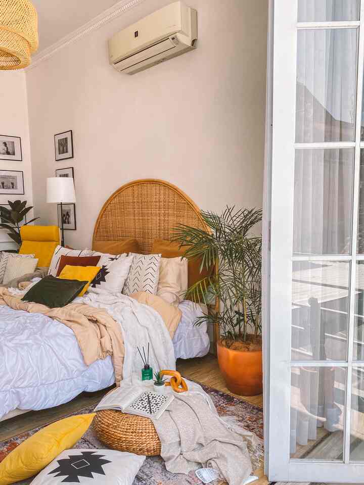 Natural wood tones and yellow accents in a bedroom featuring a rattan arch headboard and white bedding, creating a cozy atmosphere.