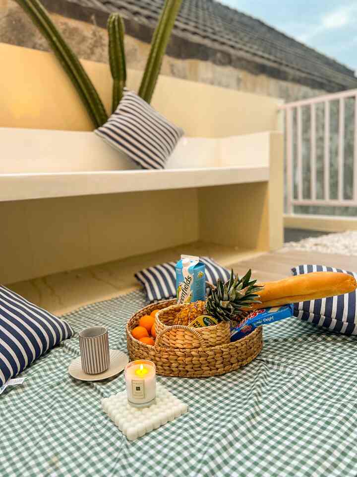 Beige and natural color veranda dining space featuring checkered cloth, cushions and woven tray basket with a cozy picnic style atmosphere