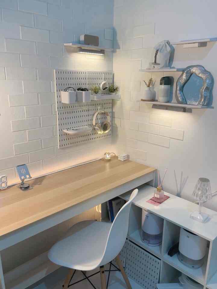 Minimal home office with white walls and wood tone desk featuring organized shelving and warm lighting