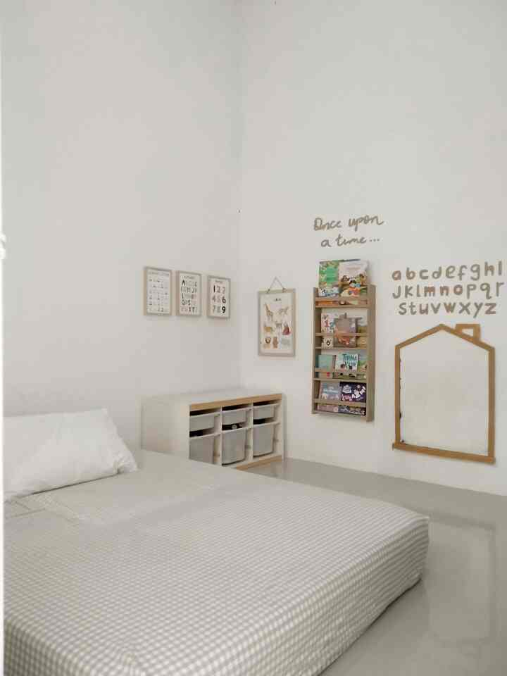 A clean kids' room in white and natural tones featuring a bed and toy storage with a minimal playroom atmosphere