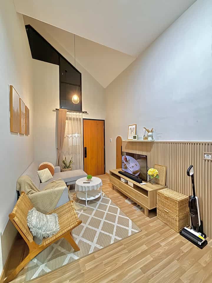 White-walled living room with wood-tone furniture, featuring a gray sectional sofa and pendant lighting in a natural setting