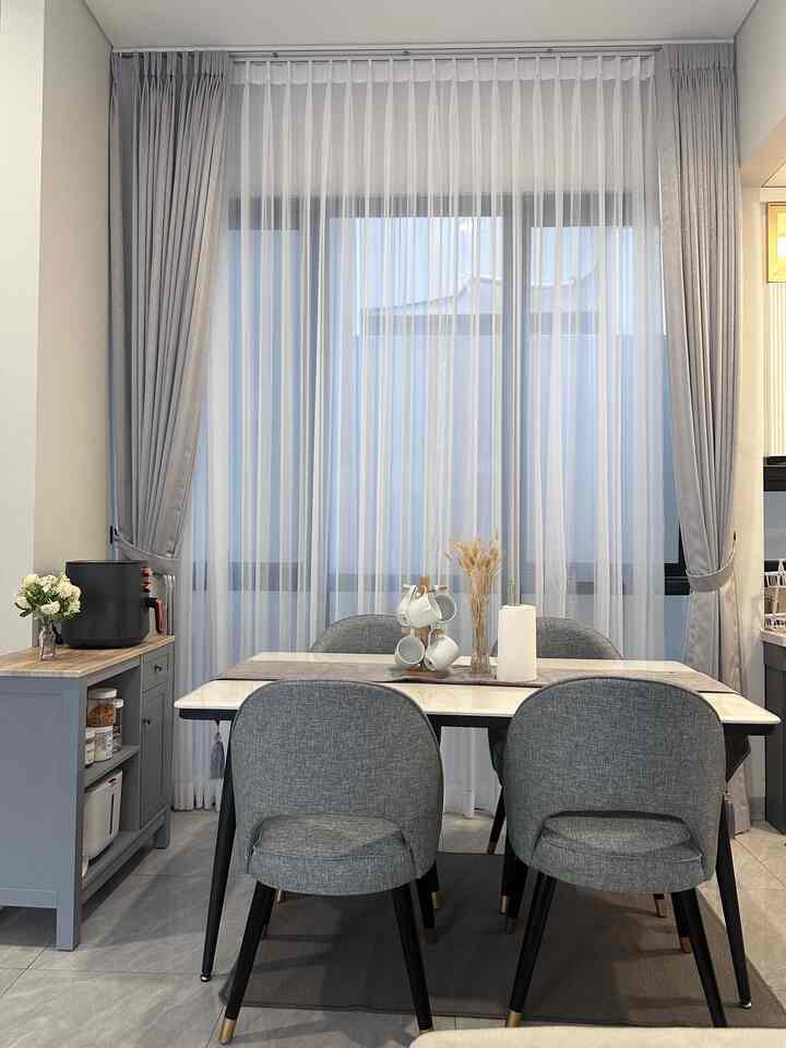 Modern hotel-like dining room featuring grey curtains, marble dining table, and four grey dining chairs