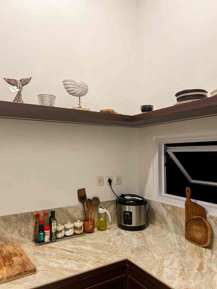 Natural-toned kitchen space featuring wooden cooking utensils and beige marble countertop with a clean kitchen setting