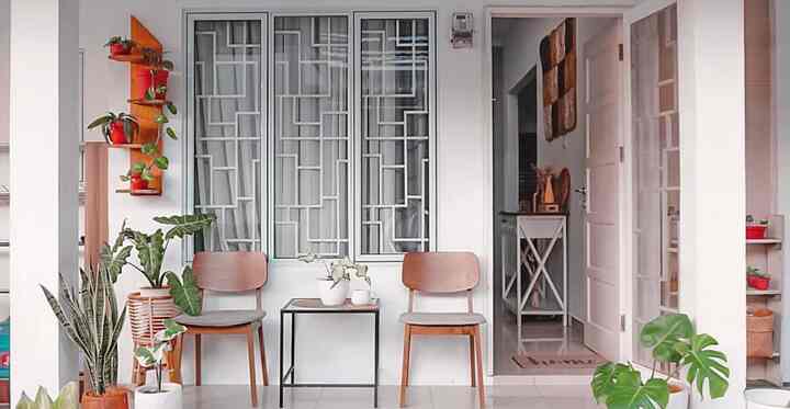 Natural modern balcony with white walls and floor, two wooden chairs, a side table, and various plants arranged decoratively