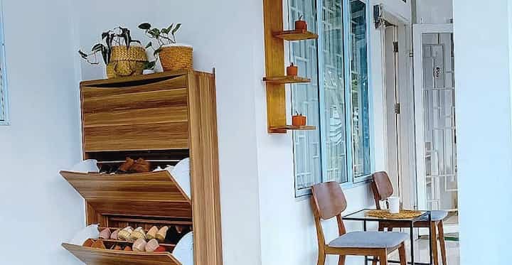 Bright white and wood tone living room featuring a shoe cabinet and seating with a clean, minimalistic atmosphere
