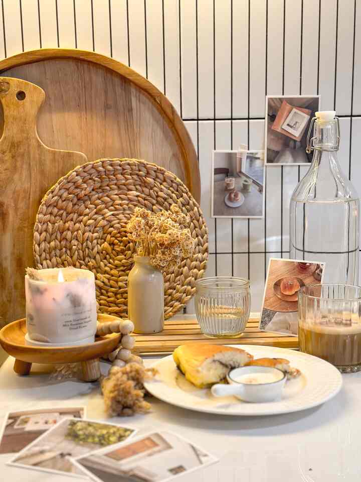 Natural-toned kitchen space featuring wooden trays, small vase with dried flowers, candle, and tableware in a cozy home cafe style