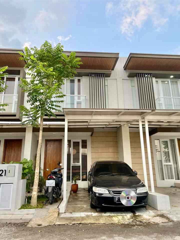Modern house facade with wood tones and black car, featuring a garage and adjacent green garden creating a clean exterior