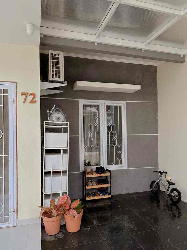 Gray wall and tiled floor entrance featuring a shoe rack, plants, and a child's balance bike