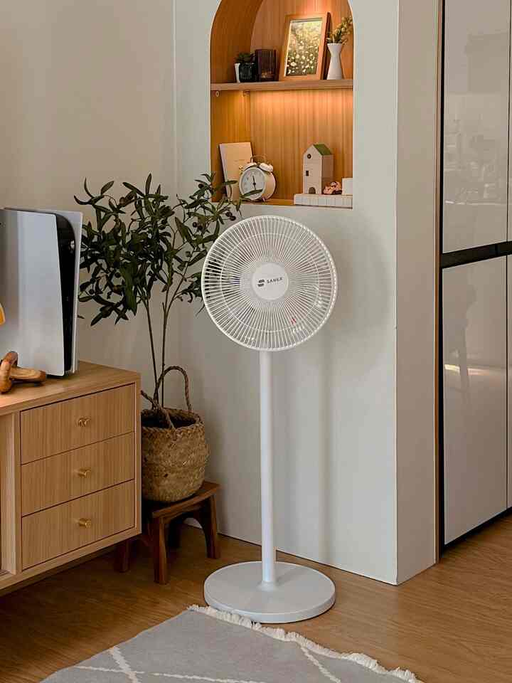 White and wood tone living room featuring a standing fan and wooden cabinet creating a warm atmosphere
