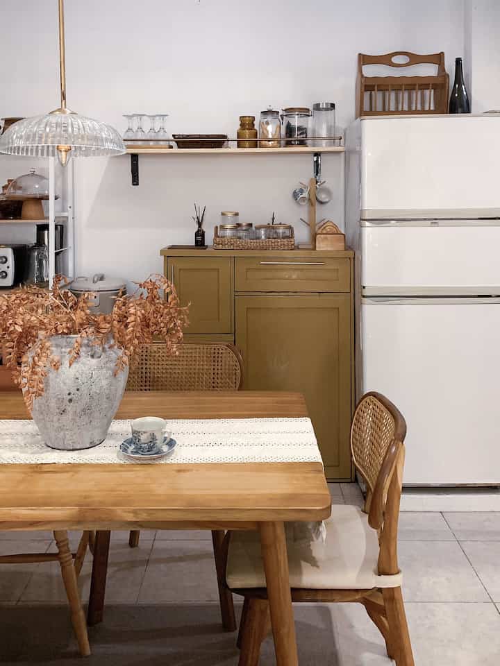 Natural toned dining room featuring wooden table and chairs with olive storage cabinet creating warm atmosphere