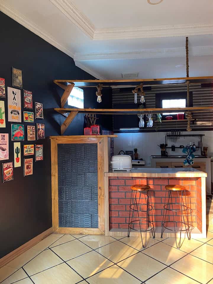 Red and black toned industrial-style home bar space featuring wood shelves and vintage wall decor in a cozy kitchen interior