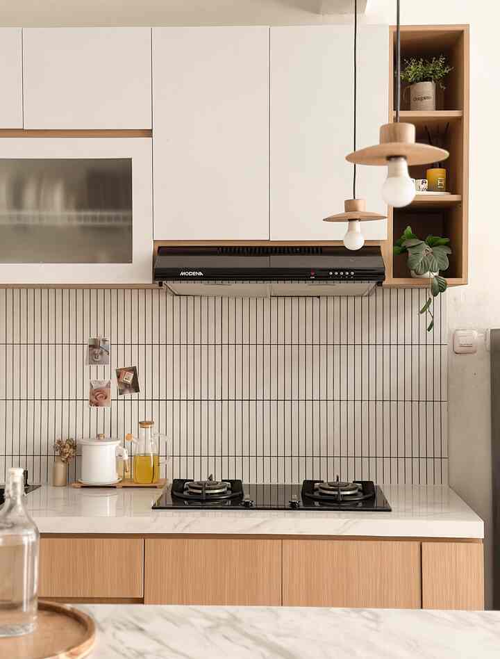 Clean kitchen space with white and wood tones, featuring slim wall sconces illuminating the modern style interior
